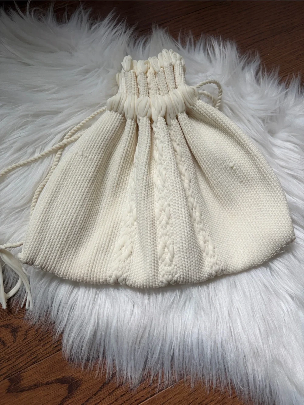 Cream cable knit drawstring bag with braided rope details